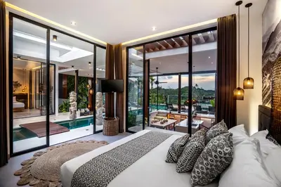 a bedroom with a large bed and glass walls at Villa Australis in Kerobokan