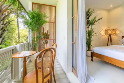 a room with a balcony with a bed and a table at White Goose Boutique Hotel in Canggu