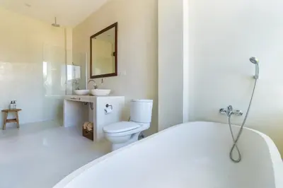 a bathroom with a tub and a toilet and a sink at White Goose Boutique Hotel in Canggu