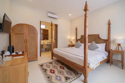 a bedroom with a large bed and a television at White Goose Boutique Hotel in Canggu