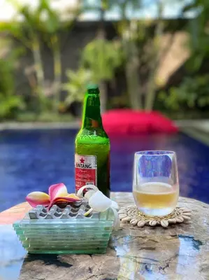a bottle of beer sitting next to a glass at CASA PINARAK 1 I 3BR Private Villa near Seminyak in Seminyak