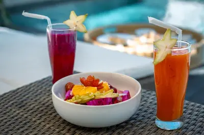 a bowl of salad and a drink on a table at Alami Luxury Villa in Seminyak