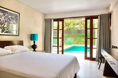 a bedroom with a bed and a swimming pool at Villa Lola in Seminyak