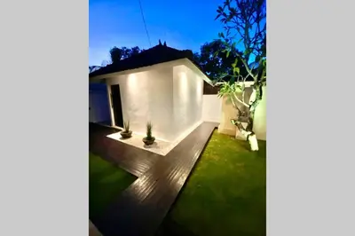 a white house with a yard with green grass at Villa Lola in Seminyak