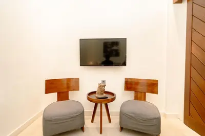 two chairs and a table with a tv on a wall at Bali Karma Sajtra Hotel in Seminyak