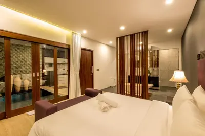a bedroom with a large white bed and a bathroom at PANDAWA VILLAS SEMINYAK in Seminyak