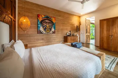 a bedroom with a large bed with a painting on the wall at Villa Hatari Canggu in Kerobokan