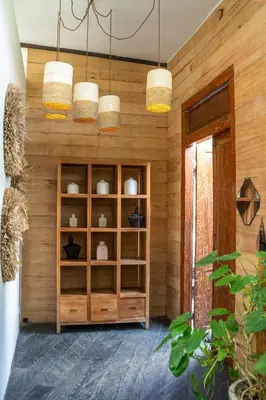 a room with a wooden wall with three chandeliers at Villa Hatari Canggu in Kerobokan