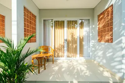 a hallway with a chair and a plant at Dharma Guest House Seminyak RedPartner in Seminyak
