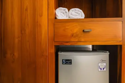 a small refrigerator in a cabinet with towels at Dharma Guest House Seminyak RedPartner in Seminyak