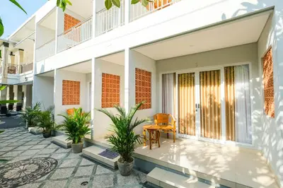 a balcony of a house with a chair and plants at Dharma Guest House Seminyak RedPartner in Seminyak