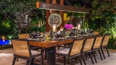 a long wooden table with chairs and wine glasses at Villa Windu Sari in Seminyak