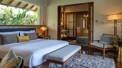 a bedroom with a bed and a chair and a window at Villa Windu Sari in Seminyak