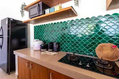 a kitchen with a green tiled wall at CASTELU 3BR peacefully villa near Mertanadi in Seminyak