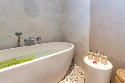 a bathroom with a bath tub and a toilet at CASTELU 3BR peacefully villa near Mertanadi in Seminyak