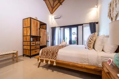 a bedroom with a large bed and a window at CASTELU 3BR peacefully villa near Mertanadi in Seminyak