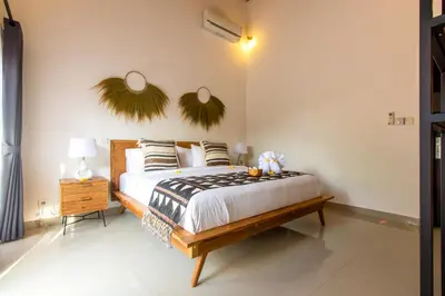 a bedroom with a bed with a wooden bed frame at CASTELU 3BR peacefully villa near Mertanadi in Seminyak