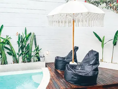 an umbrella sitting on a deck next to a swimming pool at Villa Bianca Bali in Seminyak