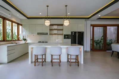a kitchen with a large white island with bar stools at Villa Reillo Canggu in Canggu