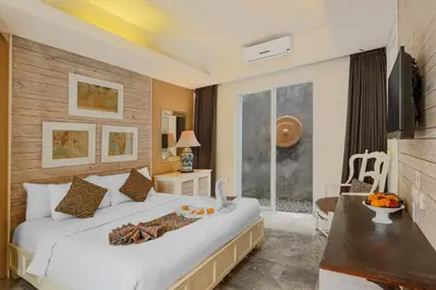 a bedroom with a large white bed and a table at The Kanjeng Suites Petitenget in Seminyak