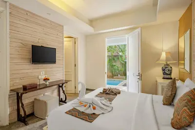 a bedroom with a bed and a tv on a wall at The Kanjeng Suites Petitenget in Seminyak