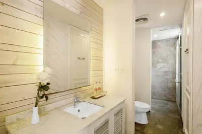 a bathroom with a sink and a toilet and a mirror at The Kanjeng Suites Petitenget in Seminyak