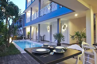 a dining table in front of a house with a pool at The Kanjeng Suites Petitenget in Seminyak