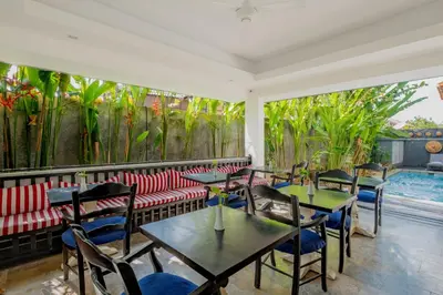 a restaurant with tables and chairs and a swimming pool at The Kanjeng Suites Petitenget in Seminyak