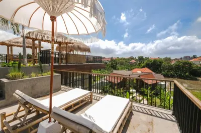 a balcony with two chairs and an umbrella at Villa Kamal Umalas in Kerobokan