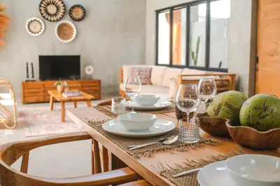 a wooden table with plates and wine glasses on it at Villa Kamal Umalas in Kerobokan