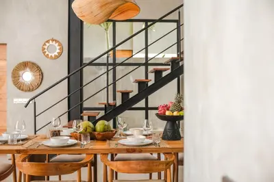 a dining room with a table with chairs and a staircase at Villa Kamal Umalas in Kerobokan