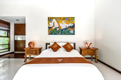 a bedroom with a white bed and two tables at Anedda Merta Sari Villa Sanur in Sanur