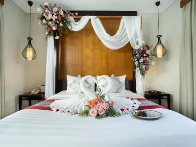a bed with white sheets and flowers on it at Samaja Villas Seminyak in Seminyak