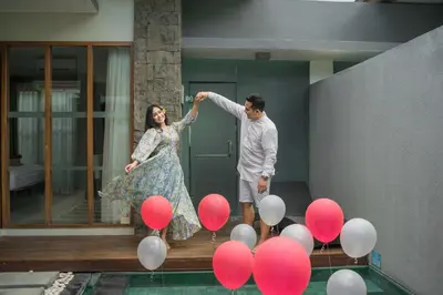 a man and woman standing next to a pool with red and white balloons at Samaja Villas Seminyak in Seminyak