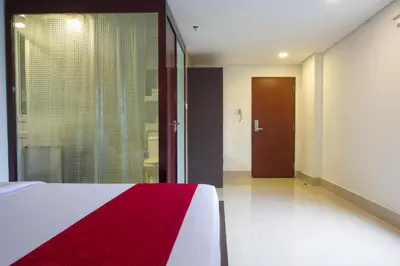 a bedroom with a red and white bed and a door at Mars City Hotel in Denpasar