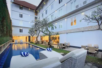 a hotel with a pool and chairs and a building at Mars City Hotel in Denpasar