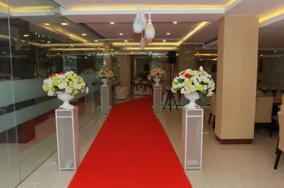 a corridor with a red carpet and flowers in vases at Mars City Hotel in Denpasar