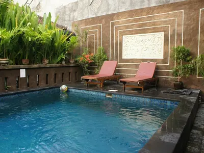 two chairs sitting next to a swimming pool at Waringin Homestay in Kuta