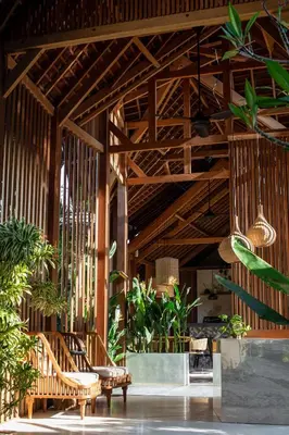 a lobby with wooden ceilings and chairs and plants at Beyond Bayou in Seminyak