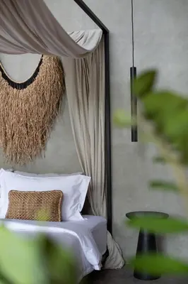 a bedroom with a bed and a table and a curtain at Beyond Bayou in Seminyak