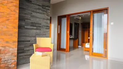 a living room with yellow chairs and a brick wall at Kubu De Uma in Seminyak