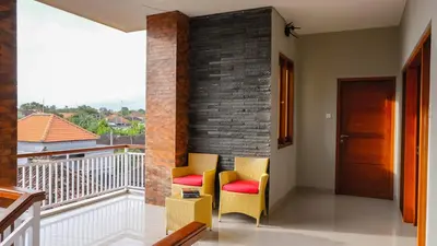 a balcony with two chairs and a brick wall at Kubu De Uma in Seminyak