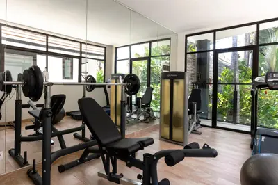 a gym with treadmills and chairs in a room with windows at Villa Anaya Manis in Seminyak