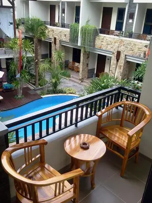 a balcony with two chairs and a table and a pool at Manggar Indonesia Hotel in Kuta