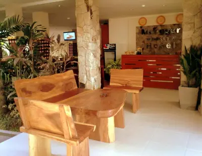a wooden table and chairs in a room with plants at Manggar Indonesia Hotel in Kuta