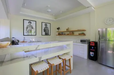 a kitchen with a counter with stools and a refrigerator at Sari Alexa Villas in Seminyak