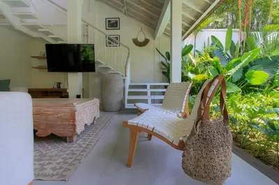 a living room with a chair and a table and a television at Sari Alexa Villas in Seminyak