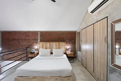 a bedroom with a bed and a brick wall at Jaci Residence by Betterplace in Canggu