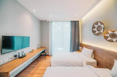 a hotel room with two beds and a flat screen tv at Bestah Coliving in Sanur