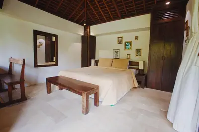 a bedroom with a bed and a table and a mirror at Phinisi Villas - Seminyak Beach in Seminyak